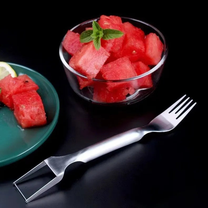 Silver stainless steel watermelon slicer and serving fork with a long handle on a kitchen surface