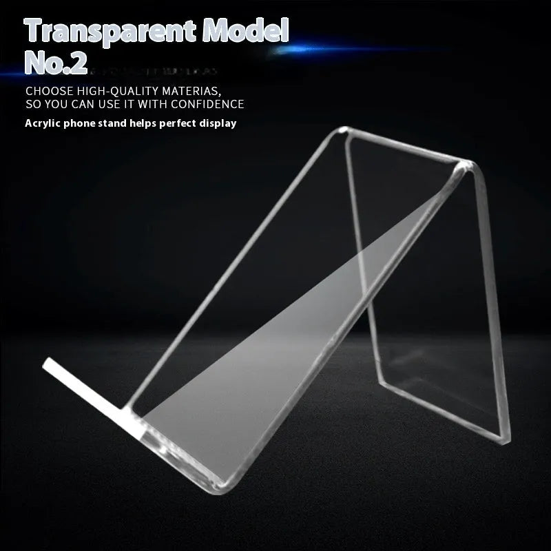 Clear acrylic mobile phone stand on a desk with a smartphone placed in it, showing the universal fit and transparent design.