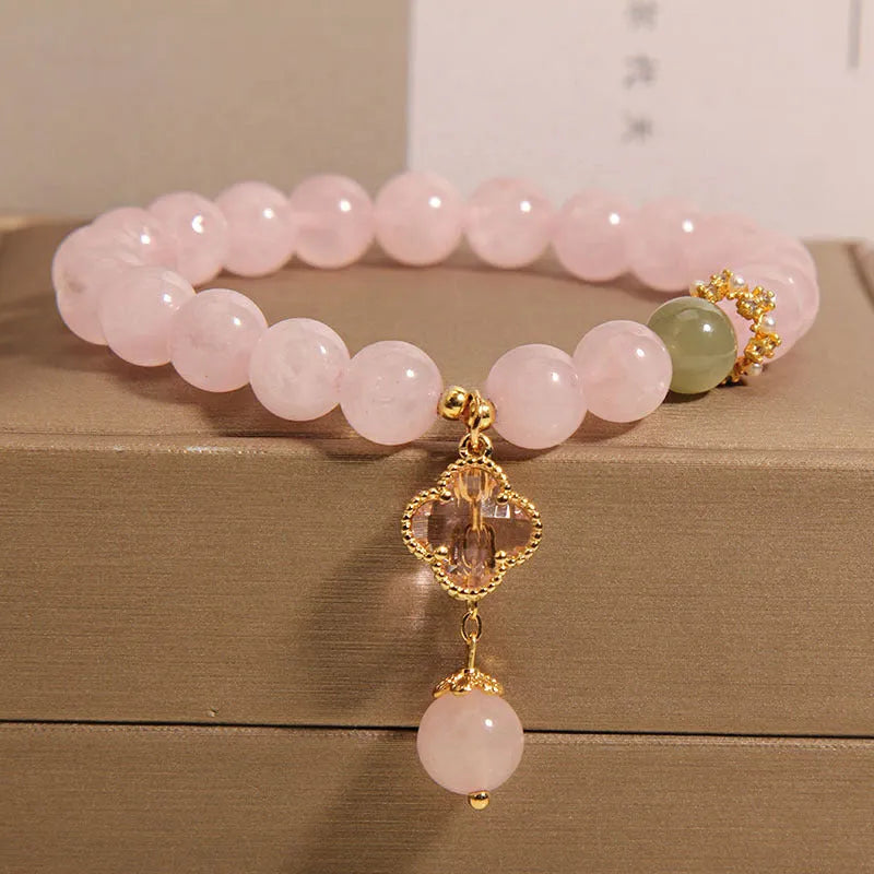 Pink women's bracelet with a crystal four-leaf clover pendant and rhinestone details on an adjustable chain.