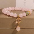 Pink women's bracelet with a crystal four-leaf clover pendant and rhinestone details on an adjustable chain.