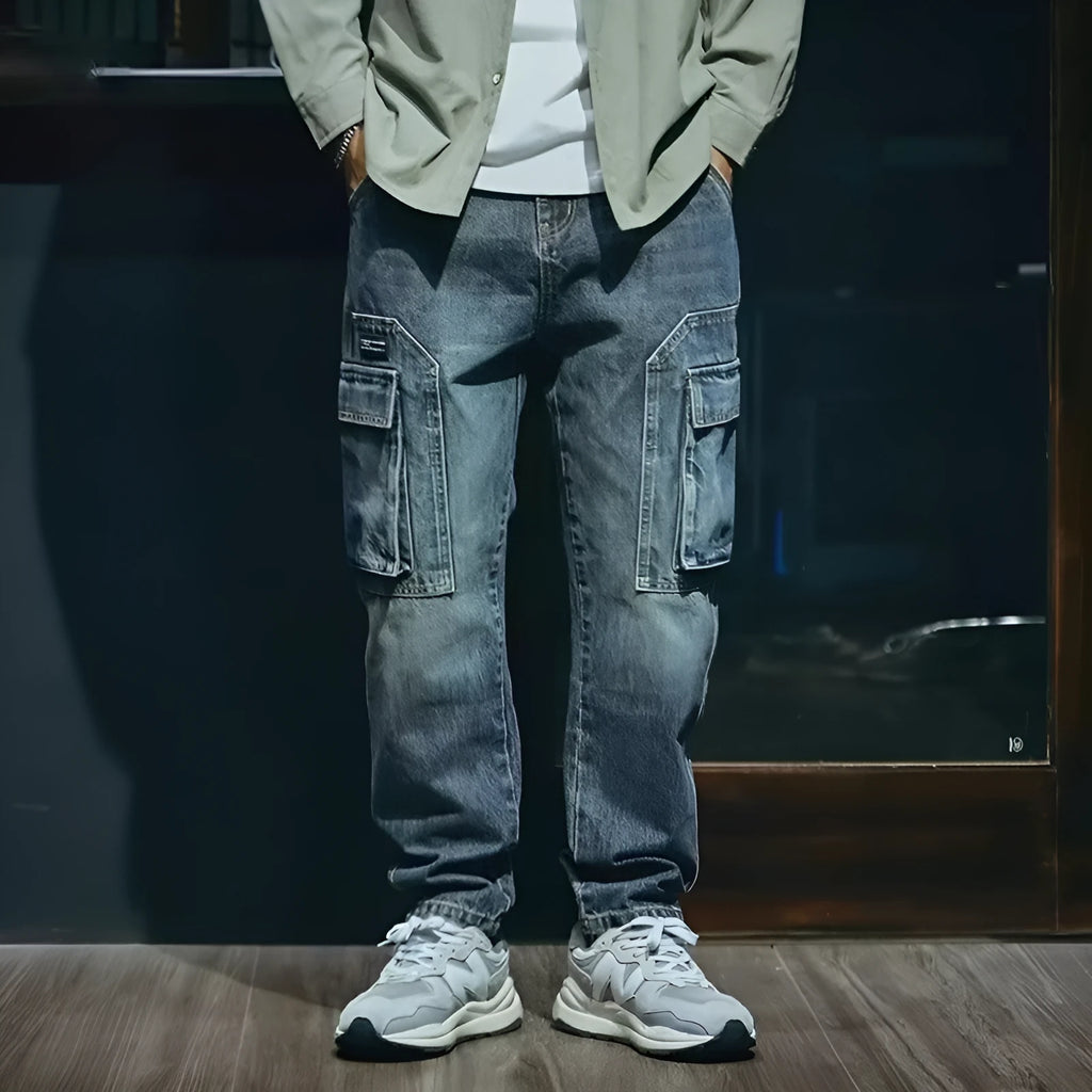 A pair of men's loose straight leg blue jeans on a plain background, showing the zip fly and classic denim style.