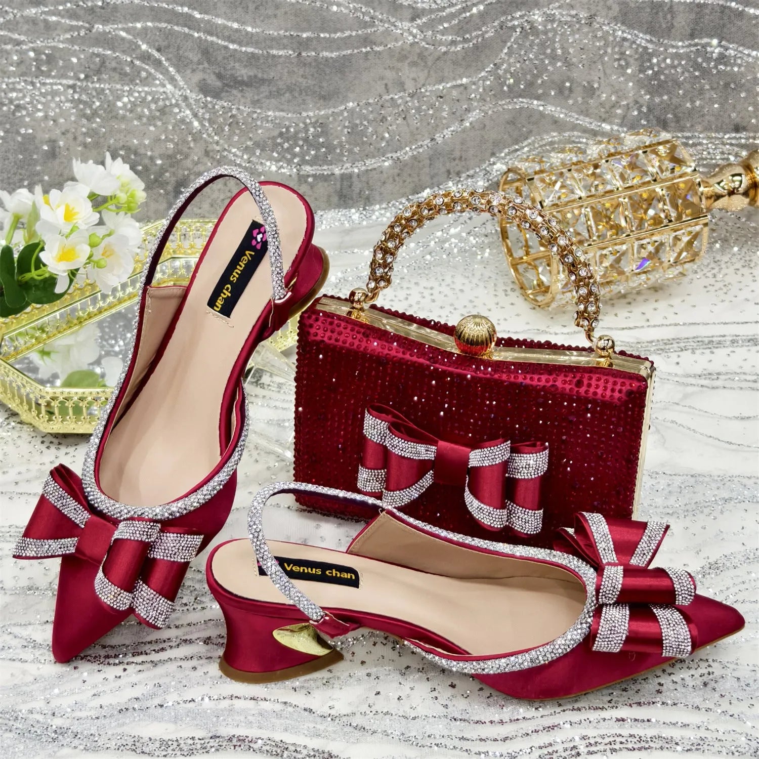 Women's black pointed toe sandals with a mid heel and matching rhinestone bag on a white background.