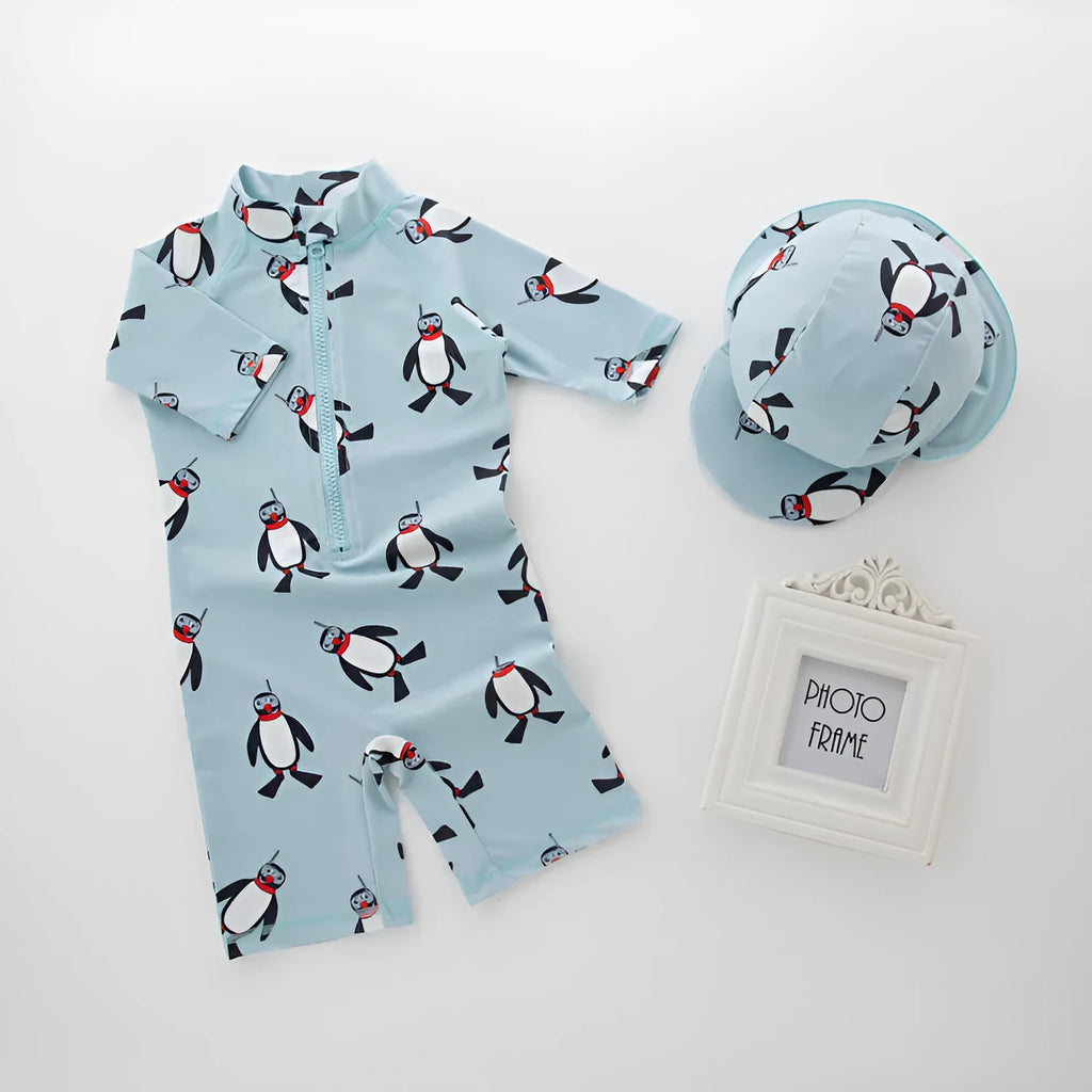 Boy's long sleeve penguin print swimsuit and matching swim cap set on a white background