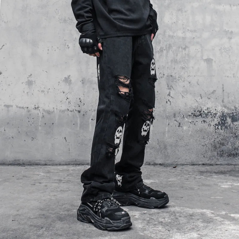 Black cotton denim jeans with skull and crossbones distressed design, mid waist, fit flared horn trousers for men.