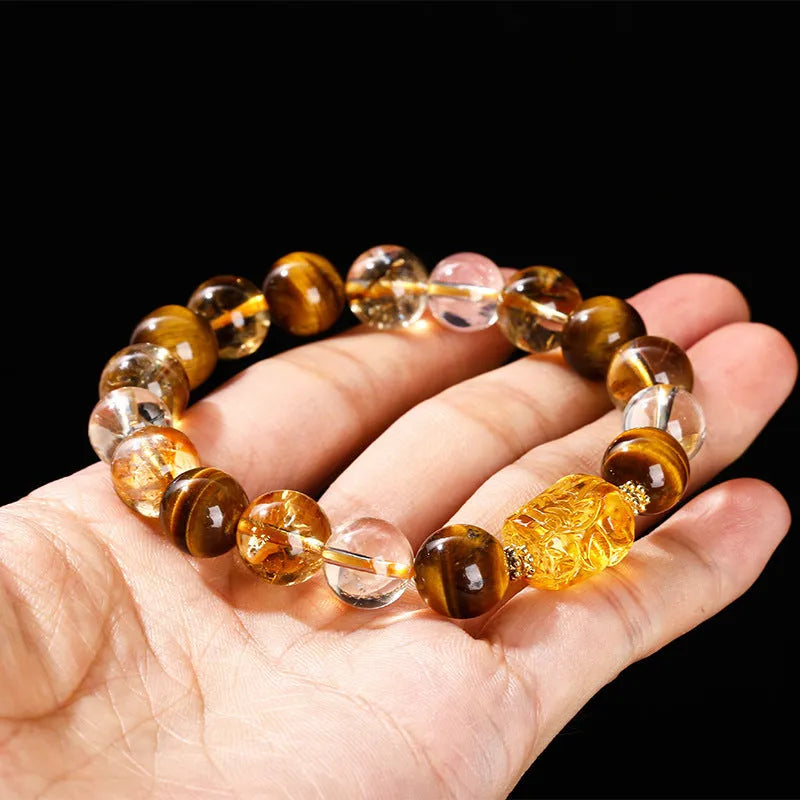 Natural yellow tiger's eye and citrine bracelet with 10mm round beads and a silver pi xiu charm on a wrist.