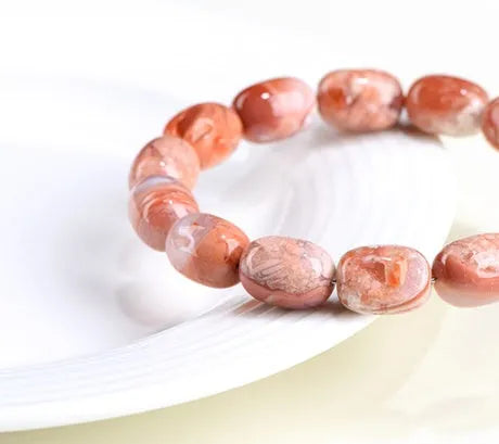 Natural cherry agate barrel bead bracelet with Ruyi symbol on a wrist.
