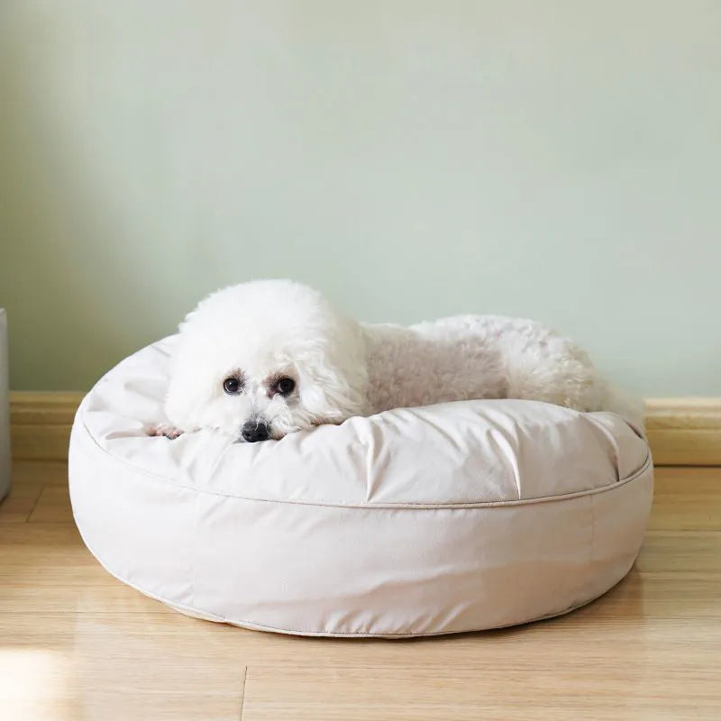 Fluffy pet bed in beige with raised rim on a light wood floor, available in sizes 60 to 80 cm diameter