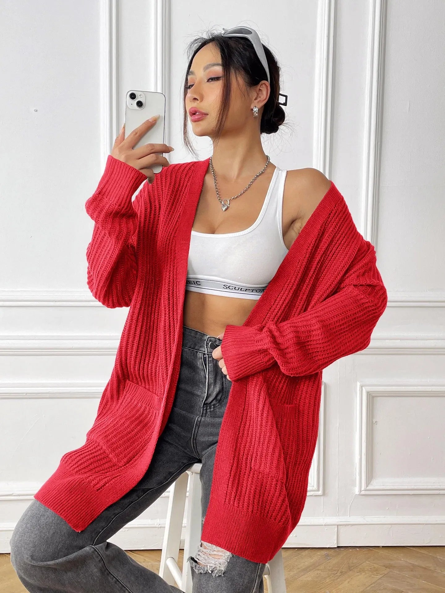 A woman's loose-fit mid-length cardigan in a solid colour, shown on a hanger.