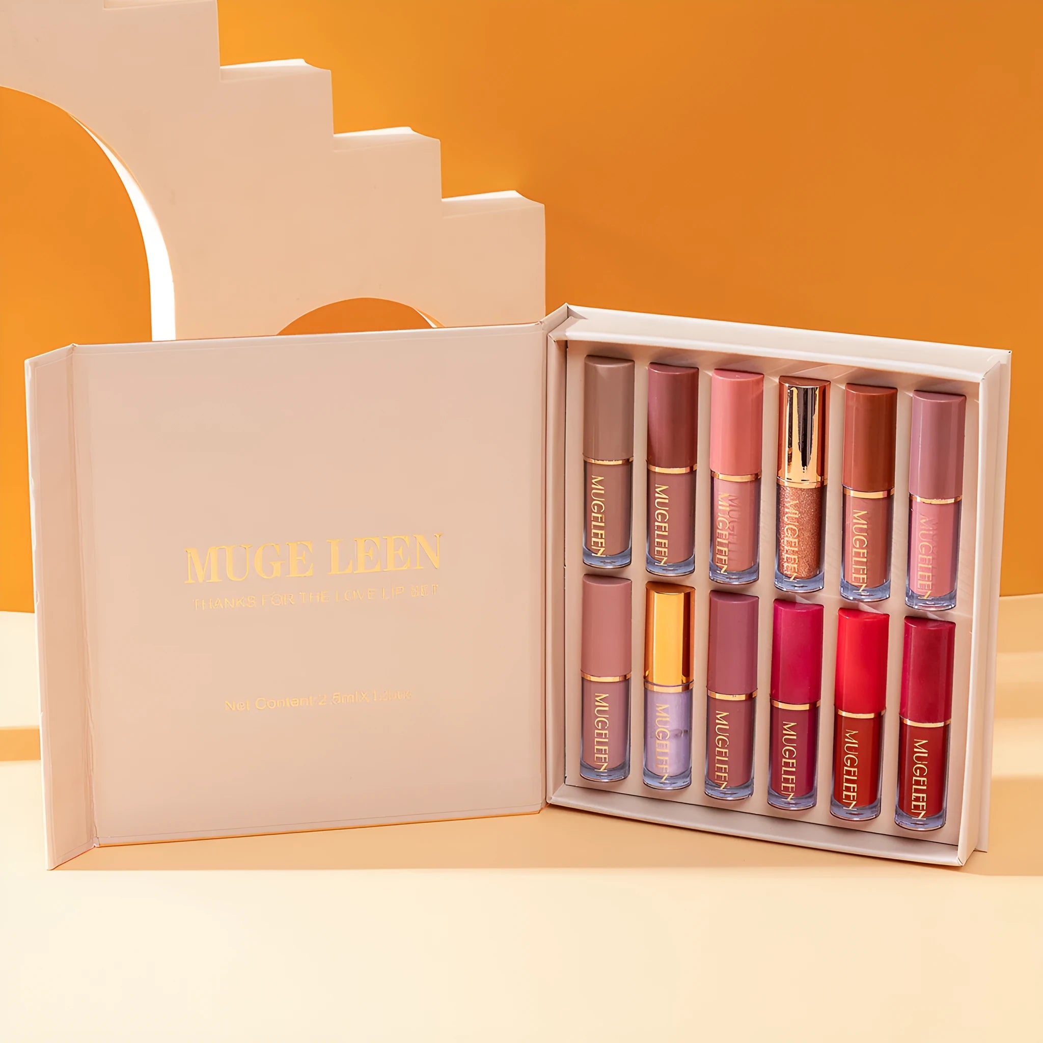 Boxed set of 12 matte shimmer lip glazes in various shades on a pink background.