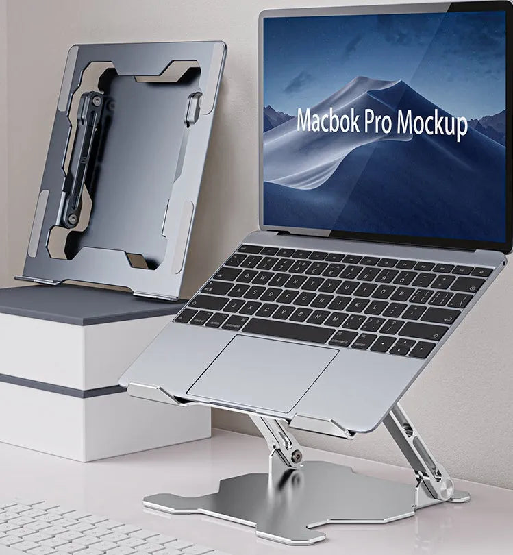 Grey aluminium laptop stand folded flat next to an open laptop, showing its adjustable angle and hollow design.