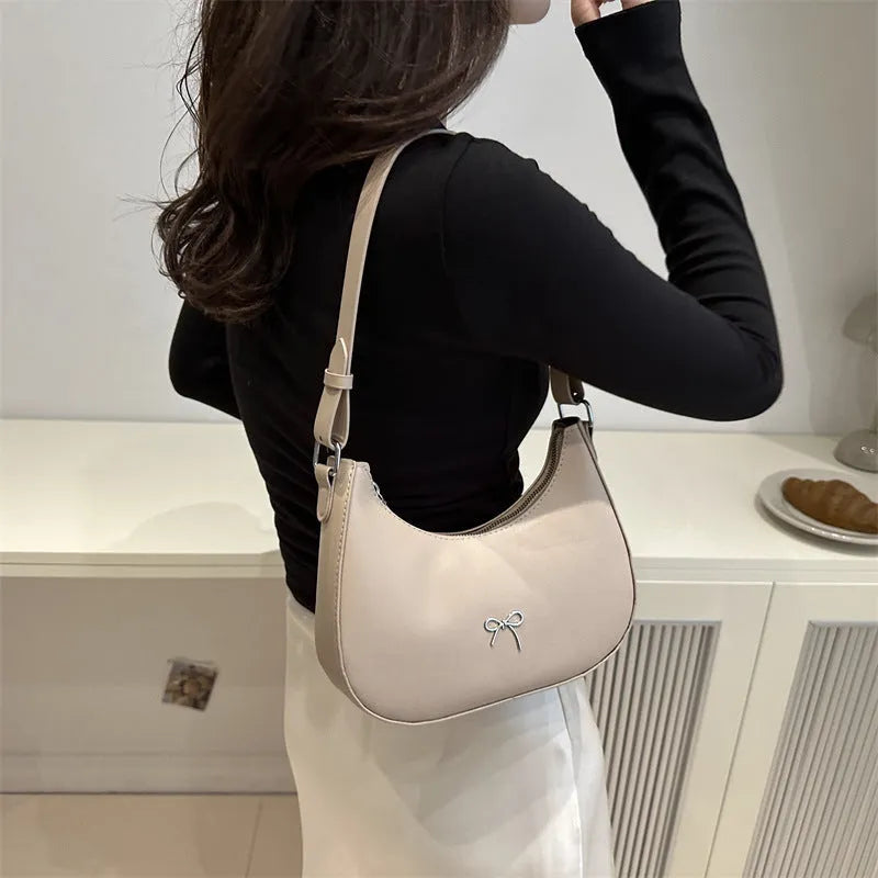 Small dumpling-shaped PU leather shoulder bag for women in multiple colours, showing the single strap and external pocket