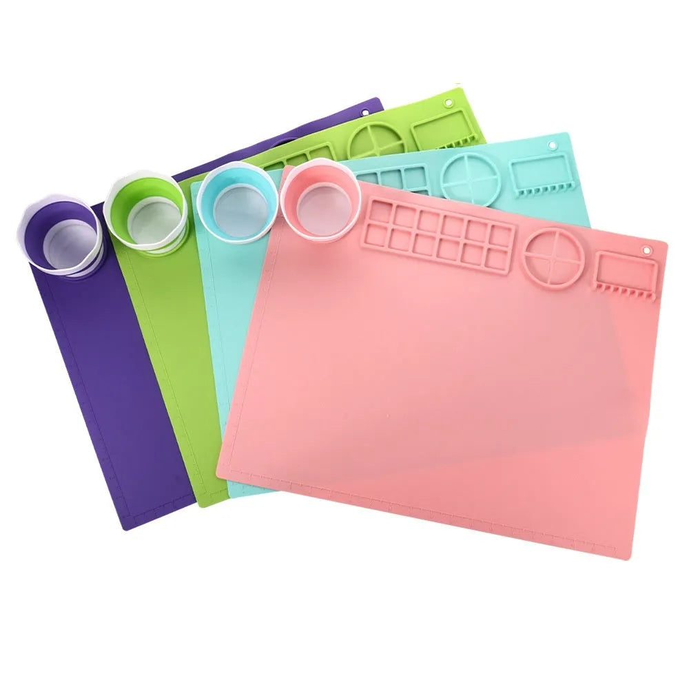 Light blue silicone painting mat with two bowl compartments on a wooden table.