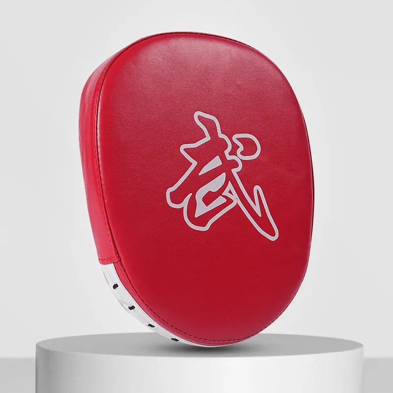Red and black curved boxing punch mitts held in a trainer's hands for Muay Thai or Sanda practice.