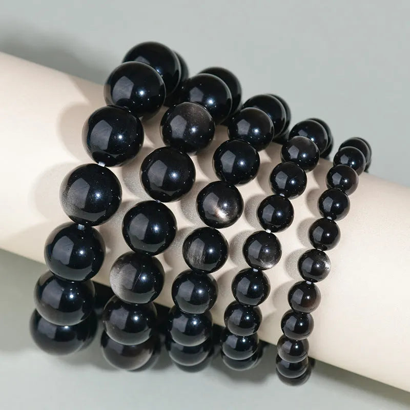 Hand-woven round obsidian crystal bracelet for couples on wrist, showing ethnic style and adjustable fit.