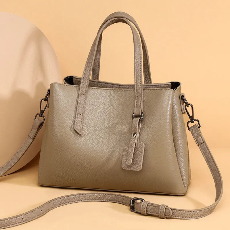 Women's cowhide leather shoulder handbag in horizontal square shape with tassel details and organised interior compartments