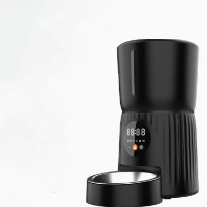 Black automatic pet feeder with digital display and detachable bowl on a kitchen floor.