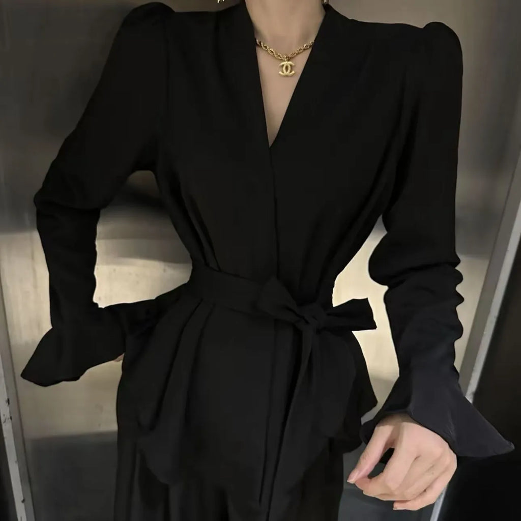 Women's black French-style shirt with an irregular collar and long bell sleeves, showing the tied front detail.