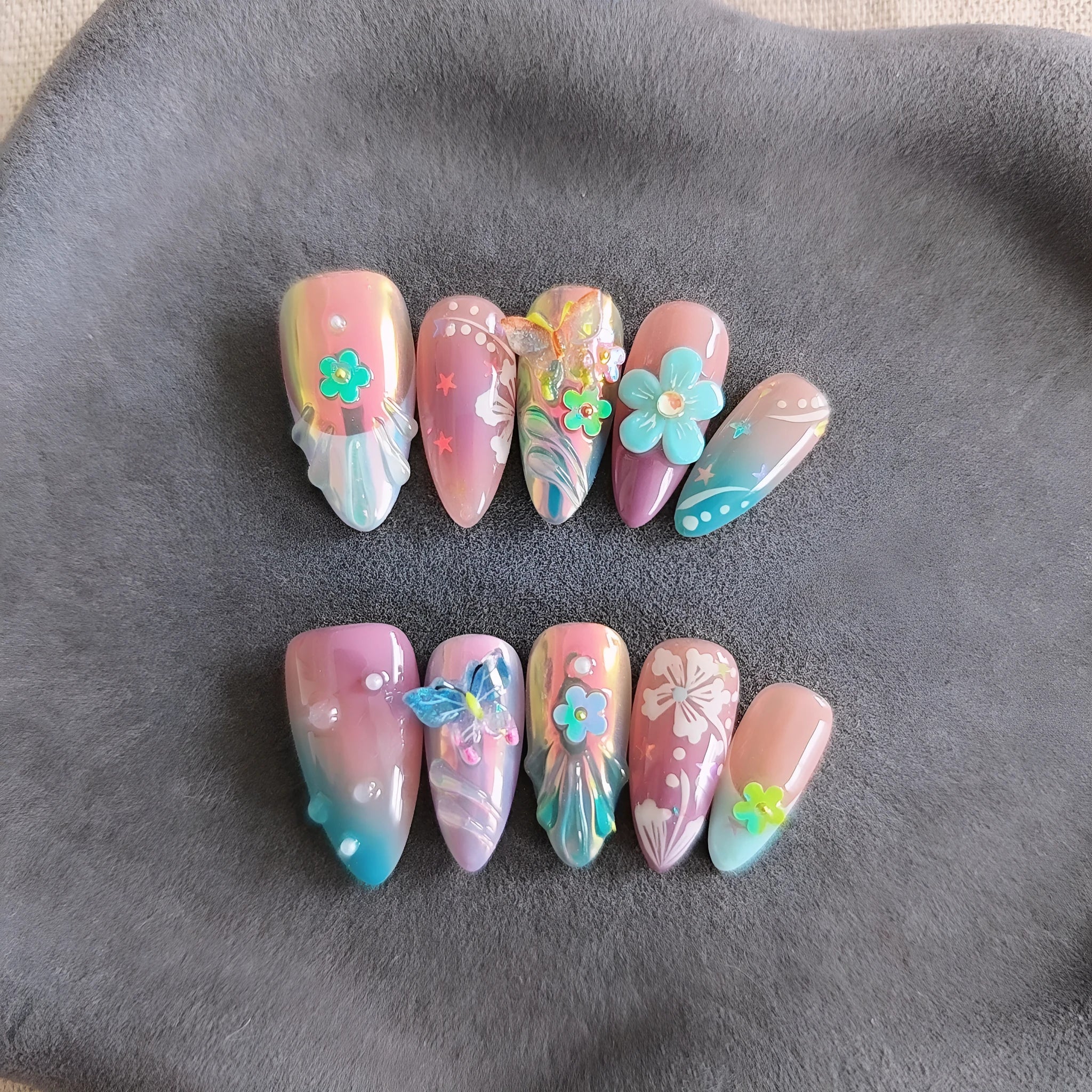Handmade colourful flower and butterfly sculpture nail art stickers on almond-shaped false nails.