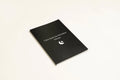 Black hardcover dream journal notebook with plain paper pages open on a desk.