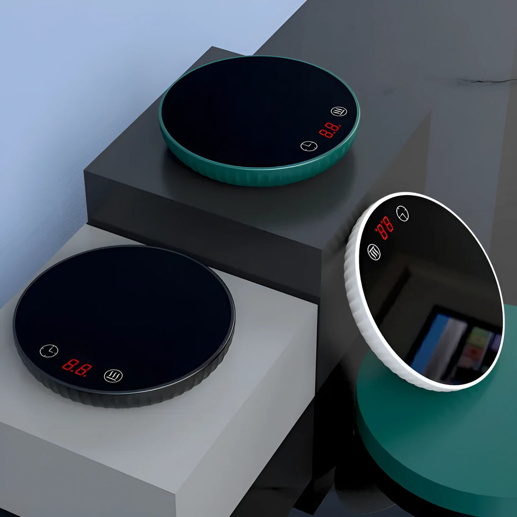 Electric waterproof cup warmer with digital display and touch switch on desk next to a mug of tea