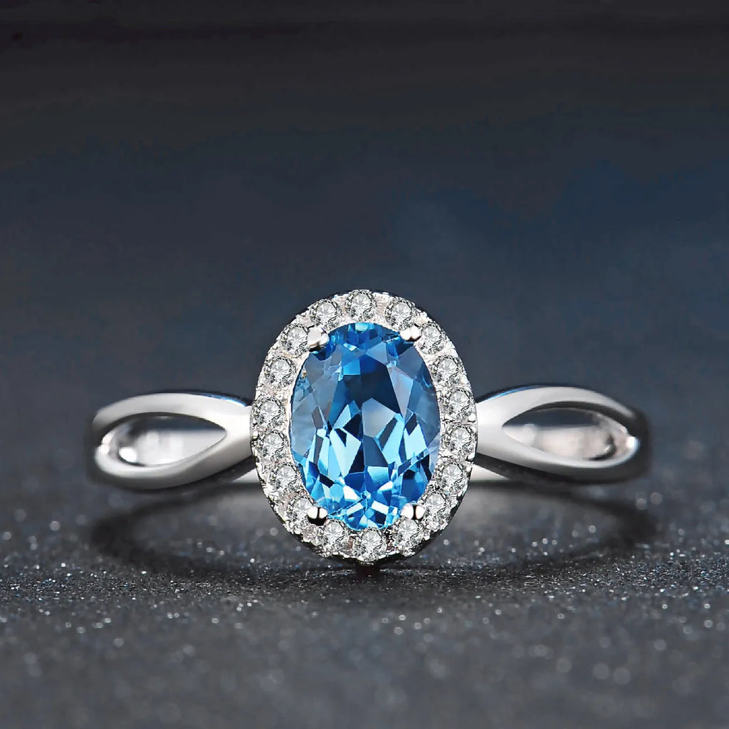 Four-piece sterling silver jewellery set with blue topaz gems showing geometric necklace, earrings, ring, and pendant