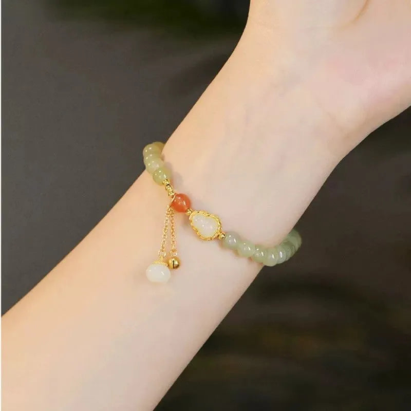 Natural jade bracelet with a gold-plated gourd charm and fu character charm.