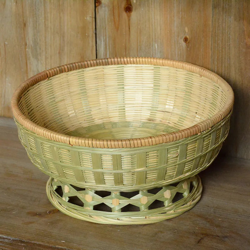 Handmade natural bamboo woven storage basket on a wooden surface.