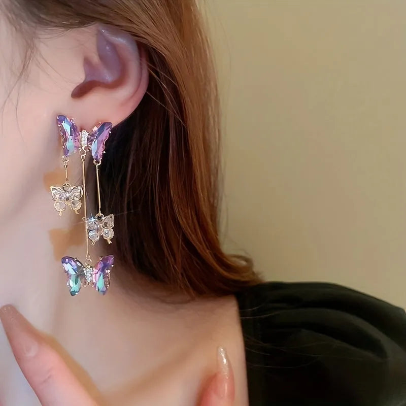 A pair of silver and blue purple butterfly tassel earrings with crystal flowers and droplet pendants.