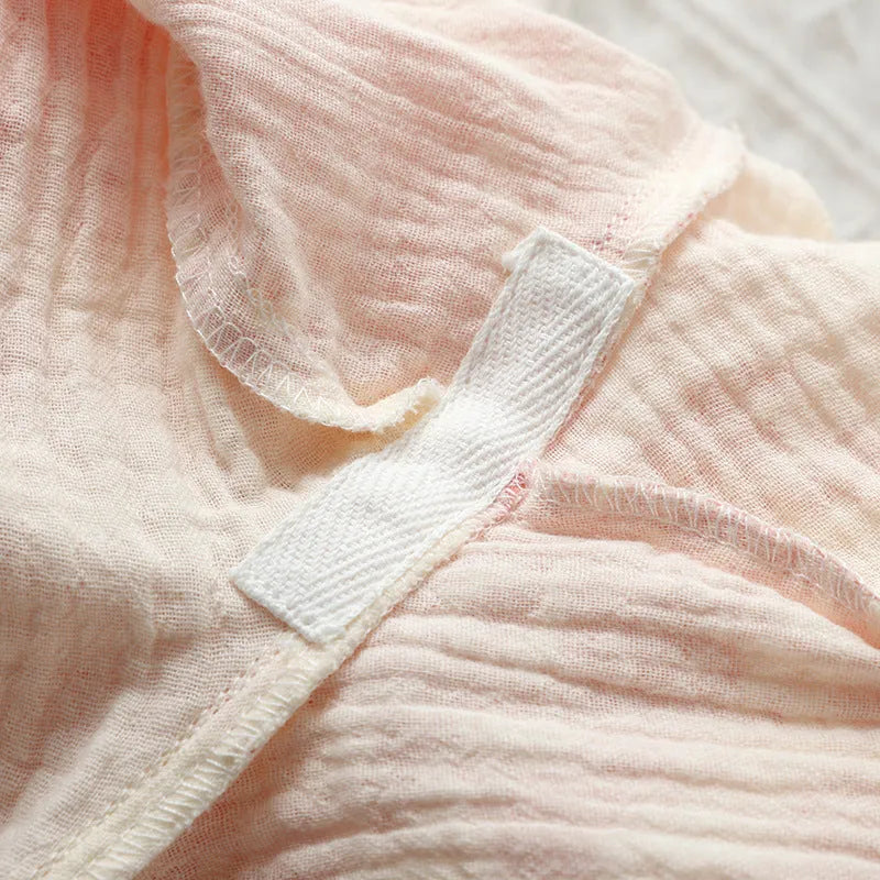 Women's pink cotton gauze lounge suit set with long sleeves and trousers laid flat.