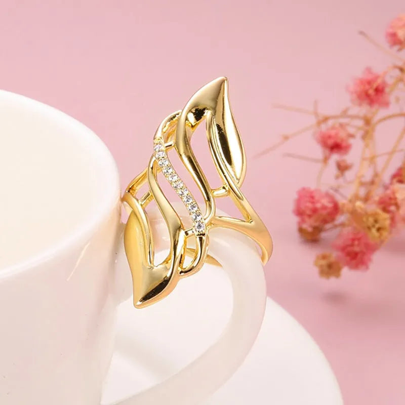 Women's gold-colour ring with exaggerated curved design on finger, showing profile and zircon finish