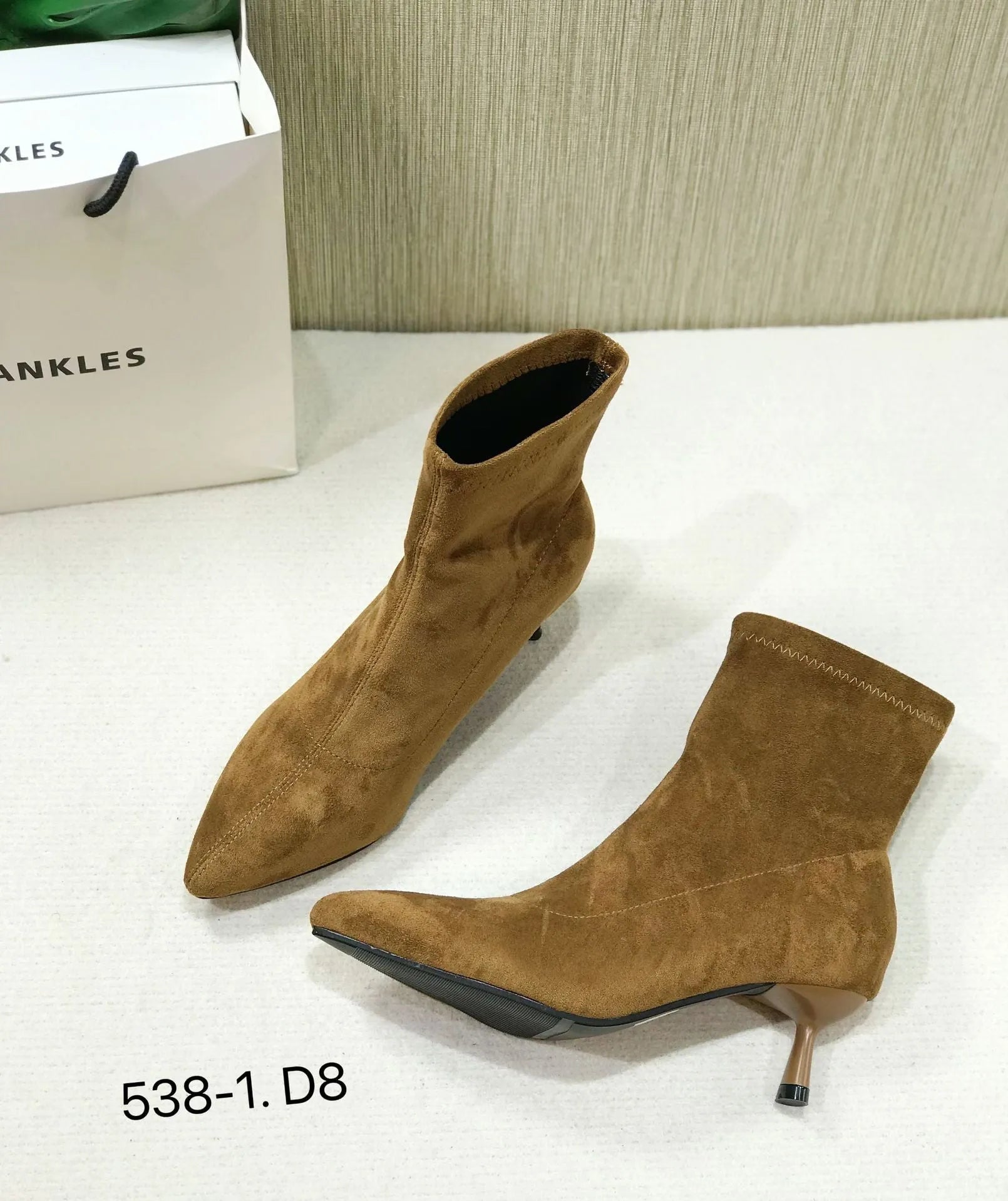 Black microfiber ankle boots with a stiletto heel and pointed toe on a mid-calf sock.