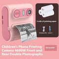 Children's instant thermal printing camera in pink with dual lenses, including lanyard and charging cable on white background