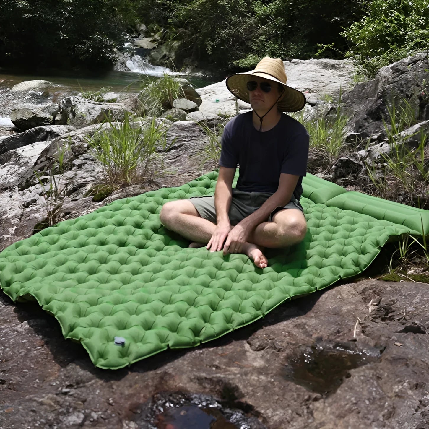 Double size inflated air mattress in army green colour with an attached pillow, on a grass surface.