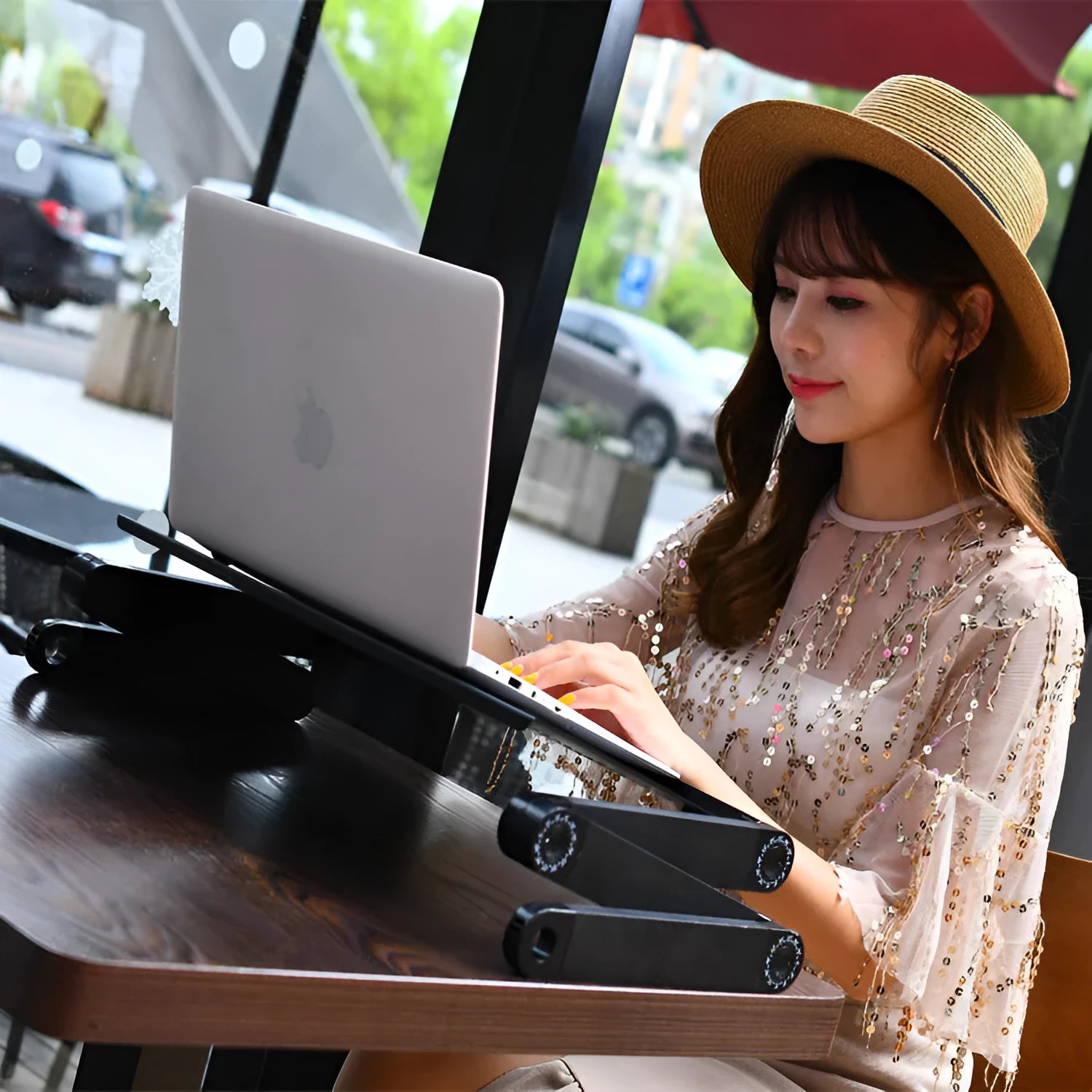 Black folding metal computer desk with cooling fan and laptop in use.