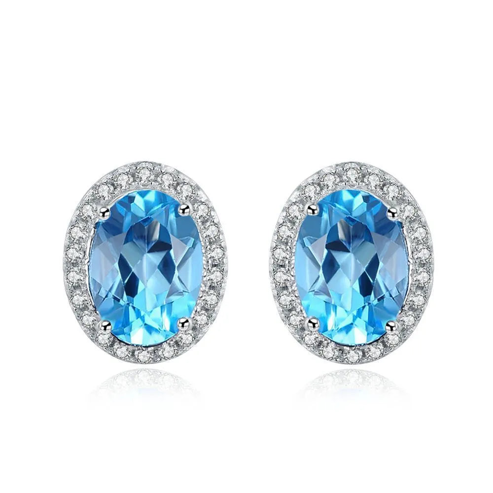 Four-piece sterling silver jewellery set with blue topaz gems showing geometric necklace, earrings, ring, and pendant