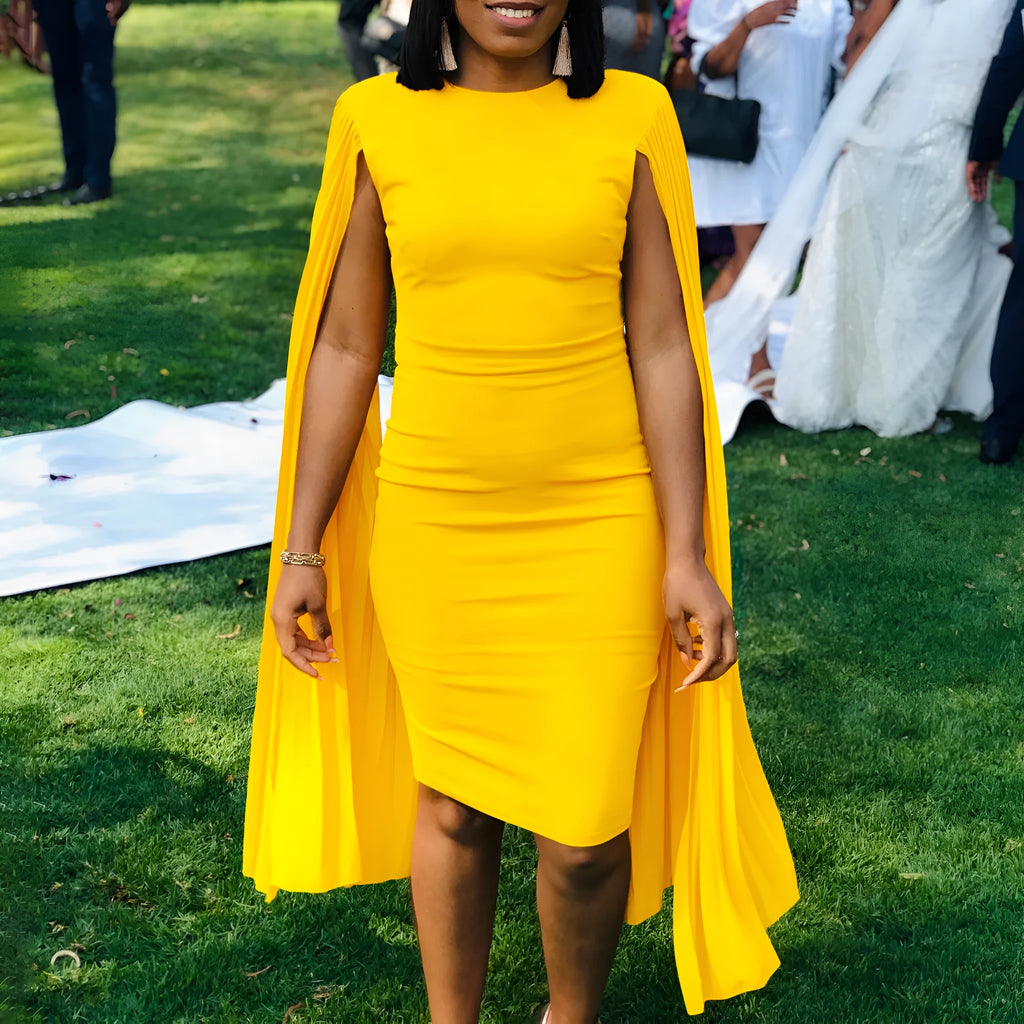 A yellow high-waisted long sleeve evening gown with a round neck and pleated skirt, laid flat.
