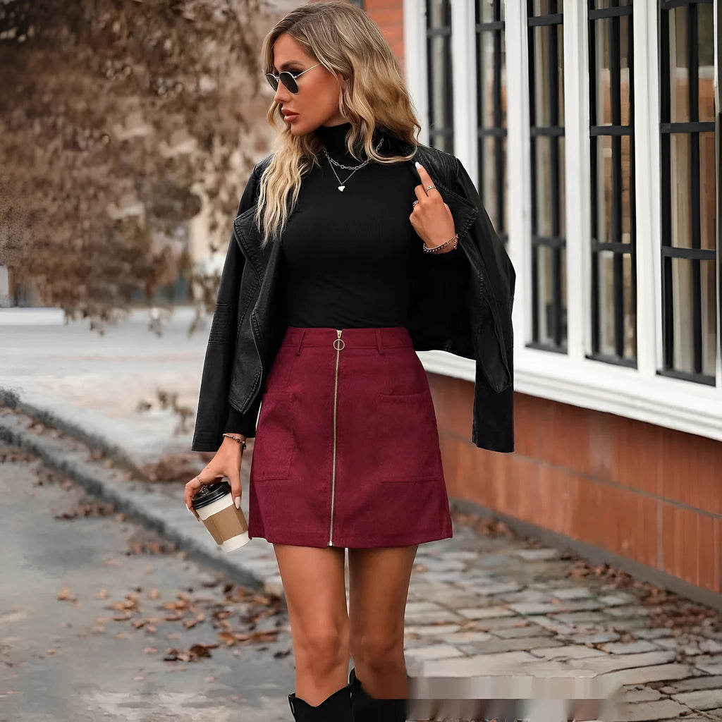 A woman wearing a high-waisted black zip-front mini skirt in a casual setting.