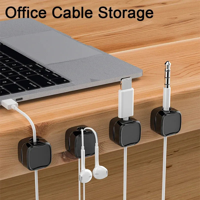 White and black magnetic cable clips holding a USB cable against a wooden desk edge.
