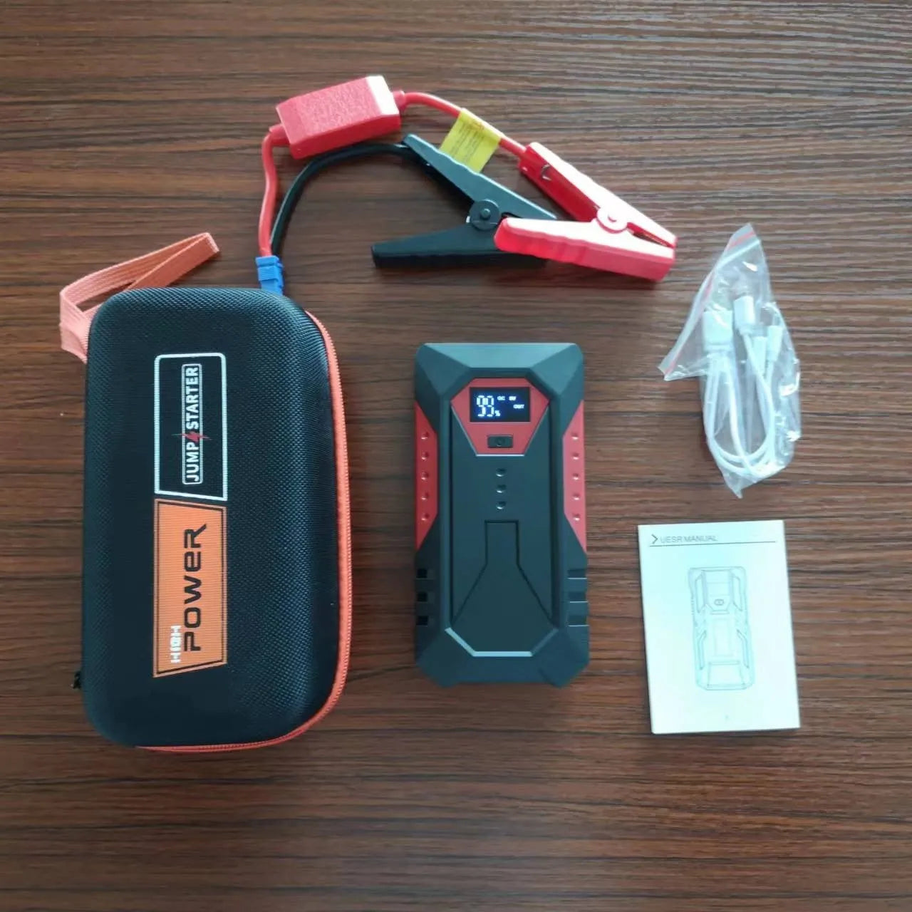 Red 12V car jump starter power bank with battery clamps, 18800mAh capacity for emergency vehicle starting