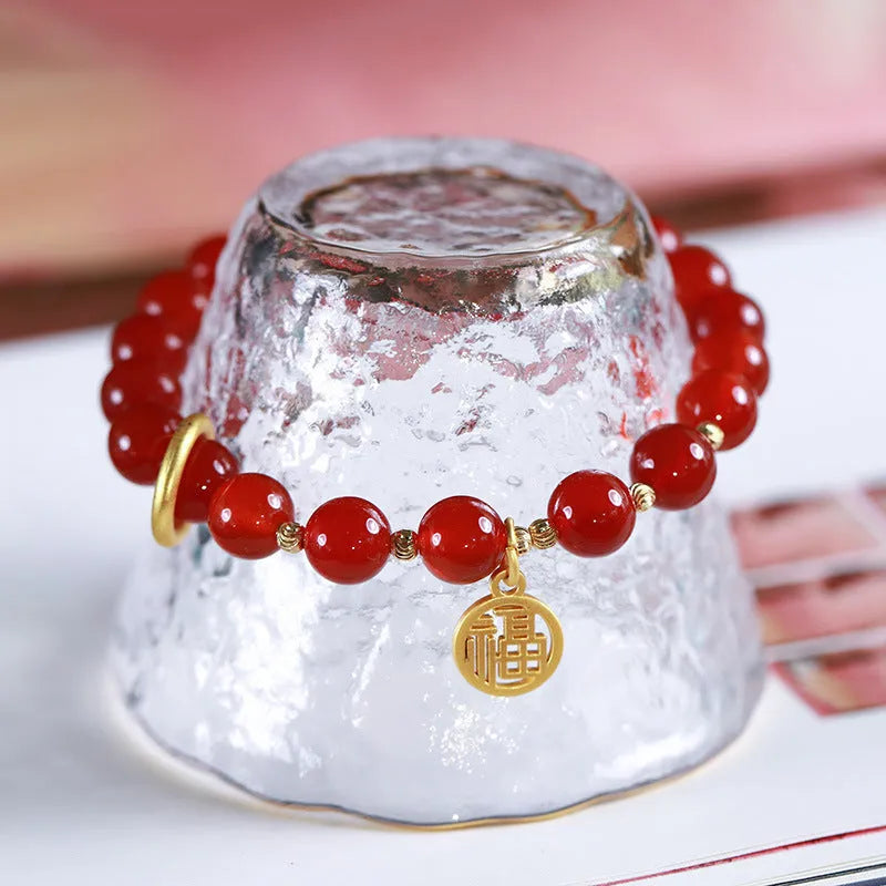 Natural red agate bead bracelet with woven design and blessing card on a neutral background.