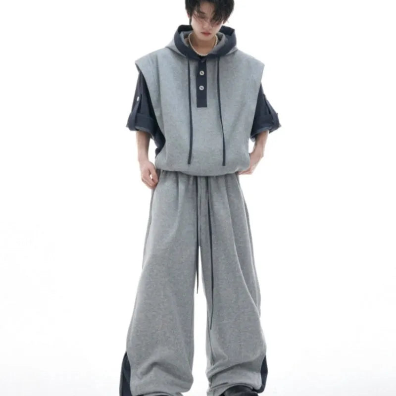 Man wearing a grey hooded short-sleeve sweatshirt and matching trousers with three-dimensional stitching detail.