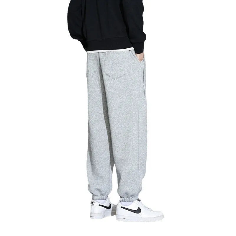 Men's grey loose-fit cotton blend sports trousers with a drawstring waistband on a hanger.