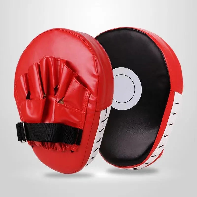 Red and black curved boxing punch mitts held in a trainer's hands for Muay Thai or Sanda practice.