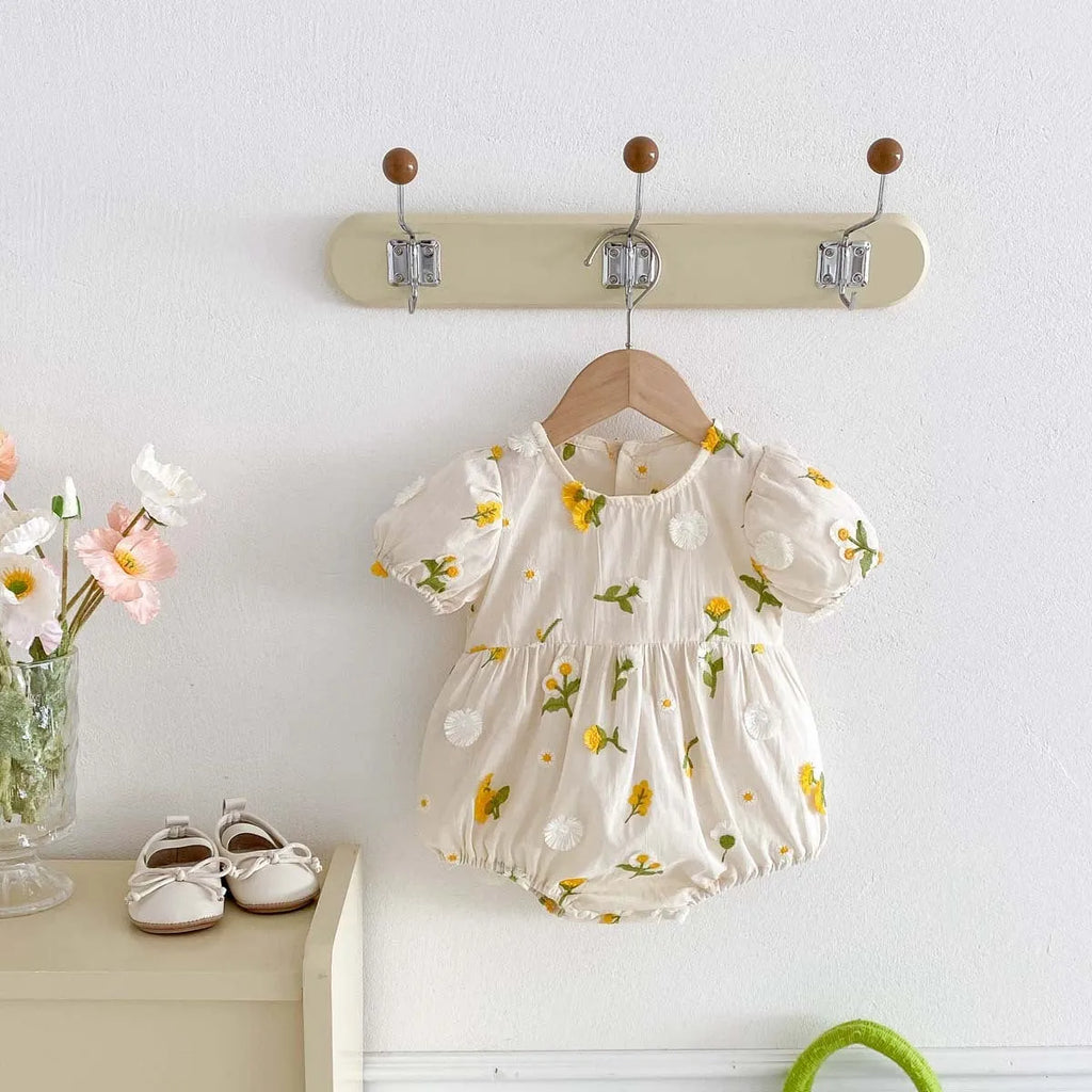 Apricot cotton baby romper with embroidered sunflower, short sleeves, triangle jumpsuit shape and hidden hook closure.