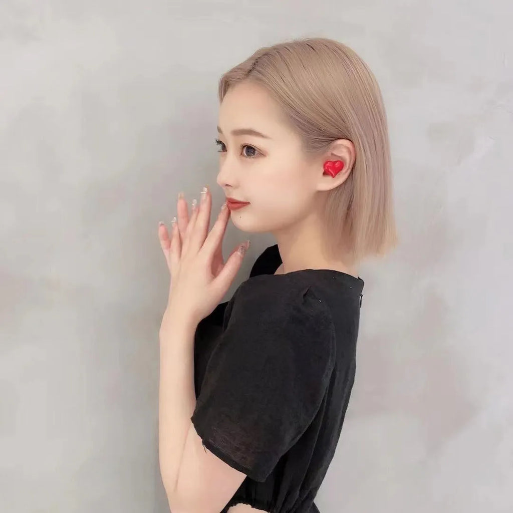 Red and pink heart-shaped wireless Bluetooth in-ear headphones with charging cable.