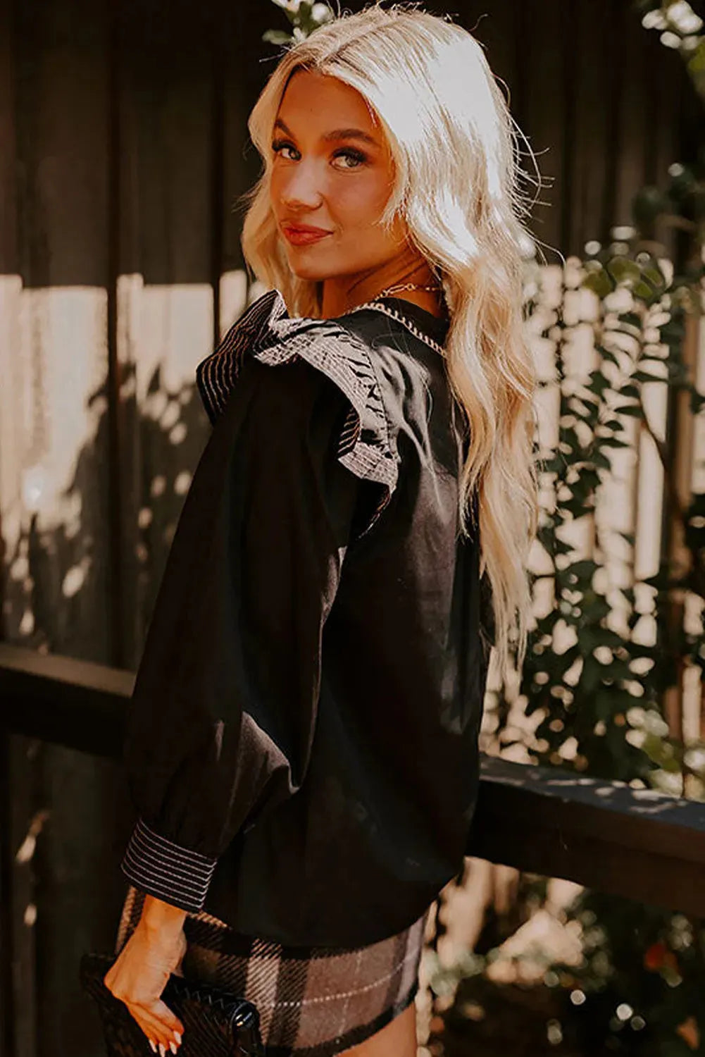 Black V-neck long sleeve blouse with contrast stitching and ruffle detail on sleeves.