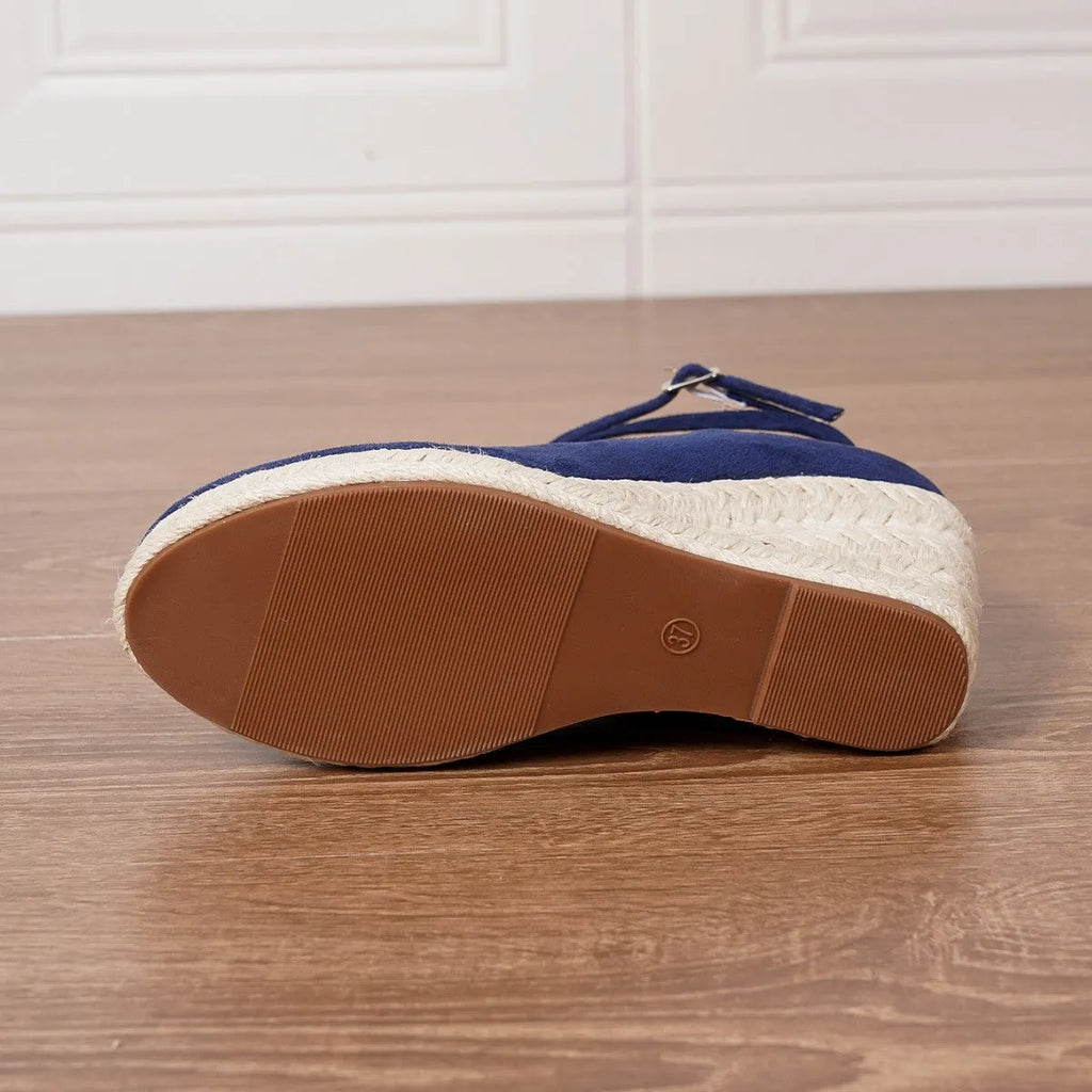 Dark blue straw woven wedge closed toe high heels with buckle fastening on a light background