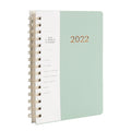 Blue A6 student weekly planner notebook with coil binding, open to show pages and pockets.