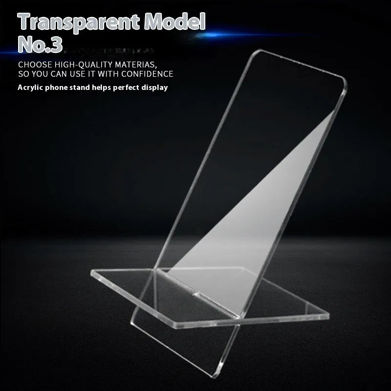 Clear acrylic mobile phone stand on a desk with a smartphone placed in it, showing the universal fit and transparent design.