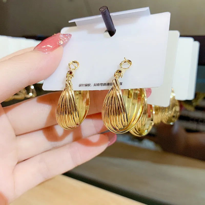 Twisted metal eardrop earring with real gold plating, geometric round shape, and stranded multi-layer design in gold colour